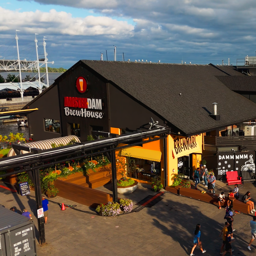 Dutch-style brewpub on Toronto's waterfront with 'Amsterdam BrewHouse' sign, outdoor seating, and people walking by.